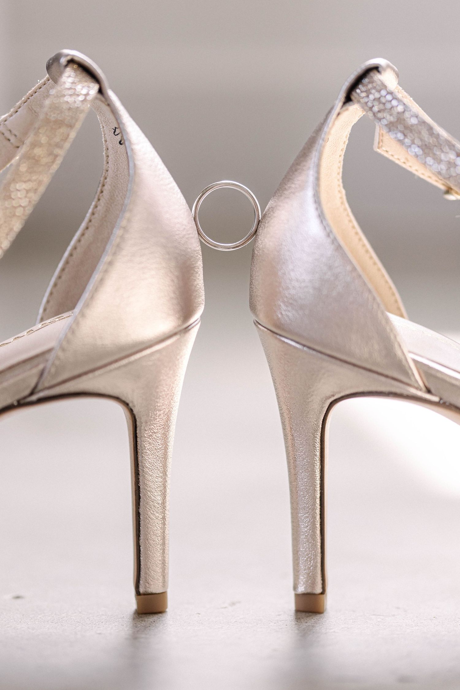 Close-up view of elegant white satin wedding heels on a light background.