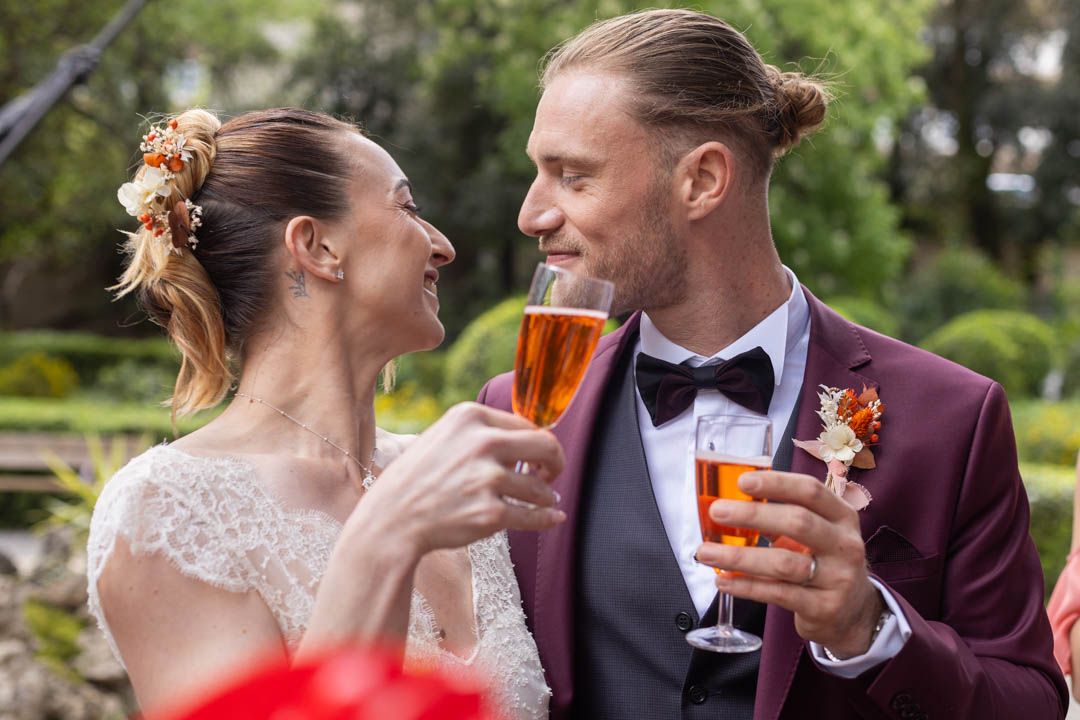 Wedding party enjoying drinks and laughter during an outdoor garden reception.