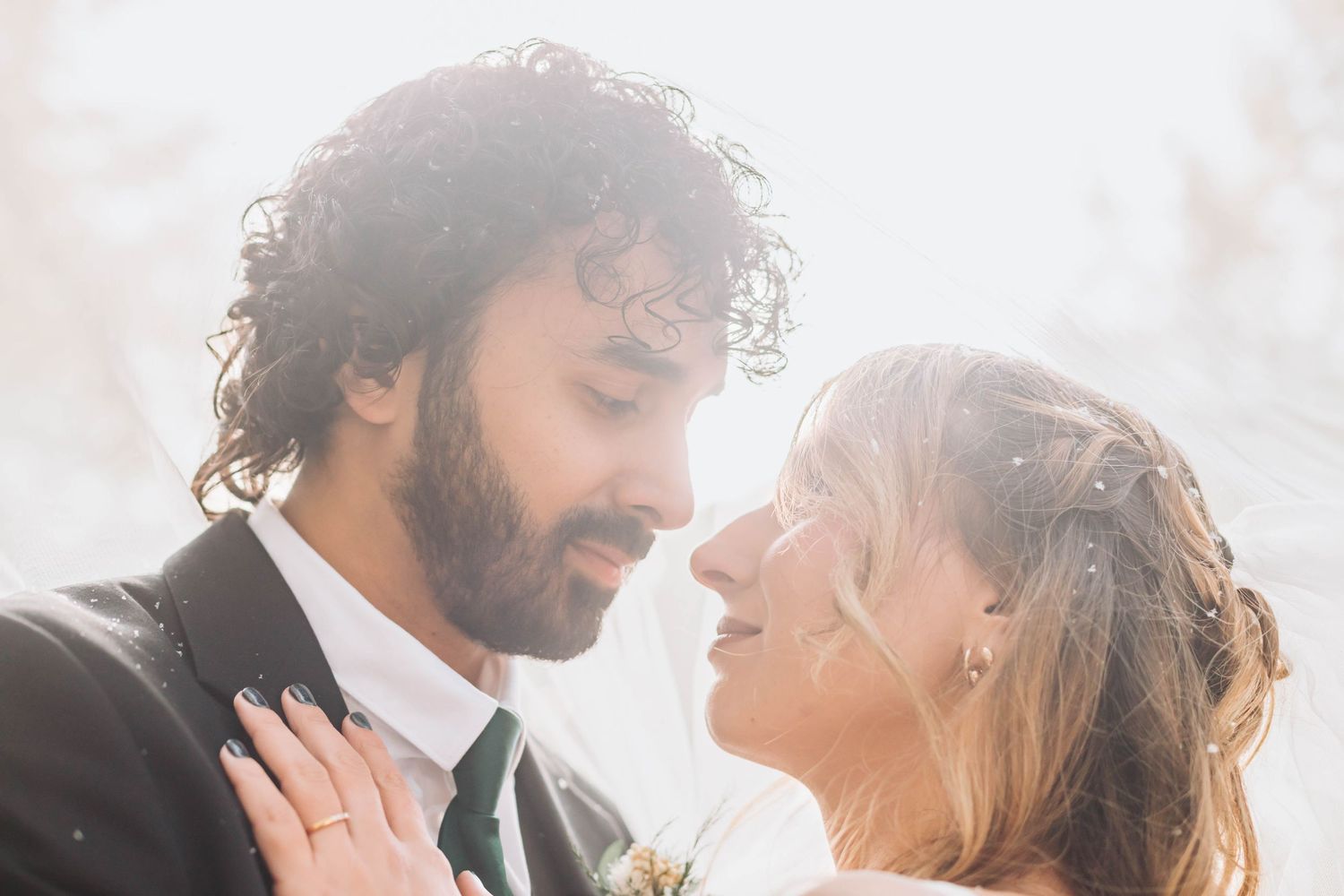 Intimate close-up portrait of newlyweds sharing a tender moment in soft light.