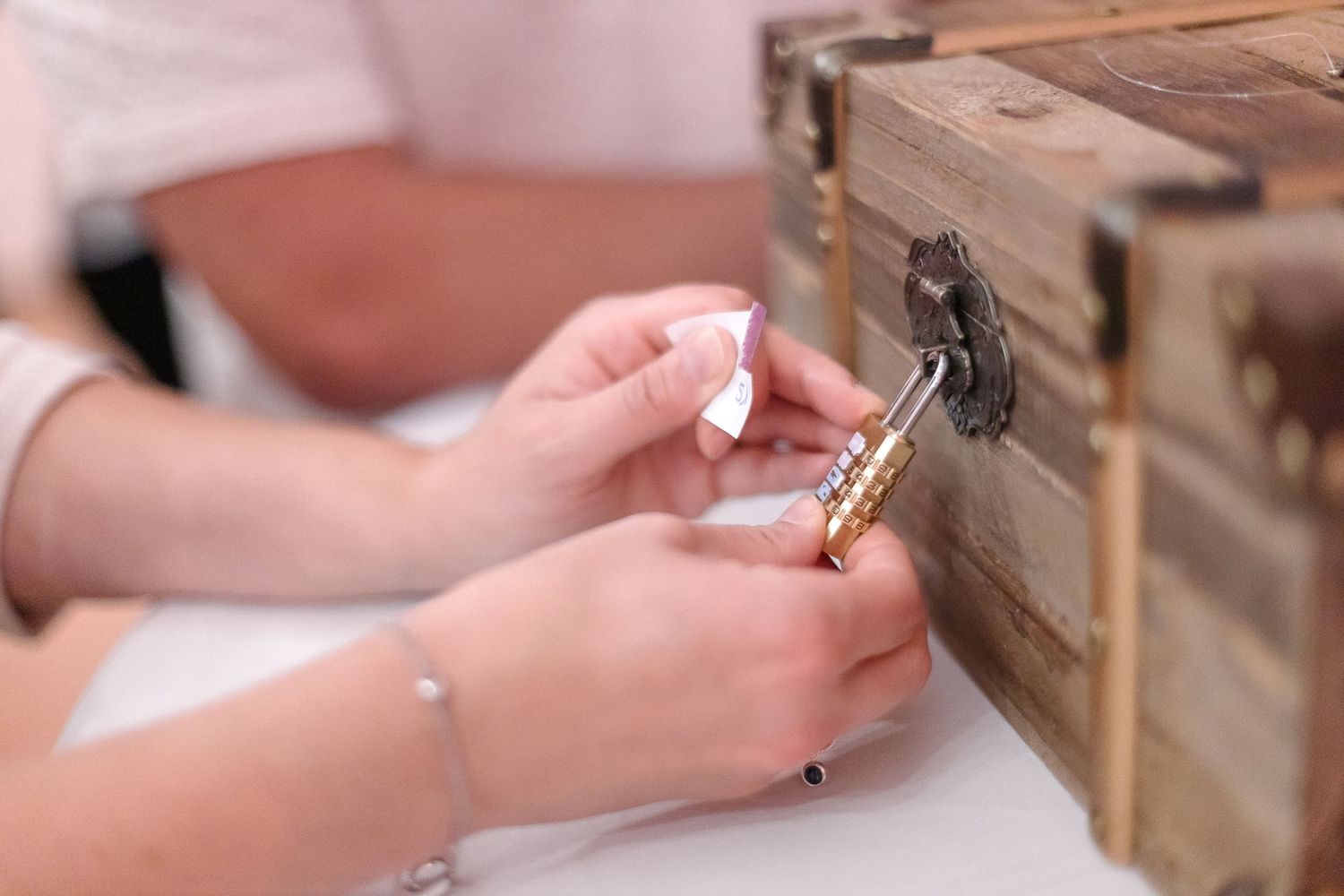 Hands carefully unlocking an antique wooden box with an old key at close range.