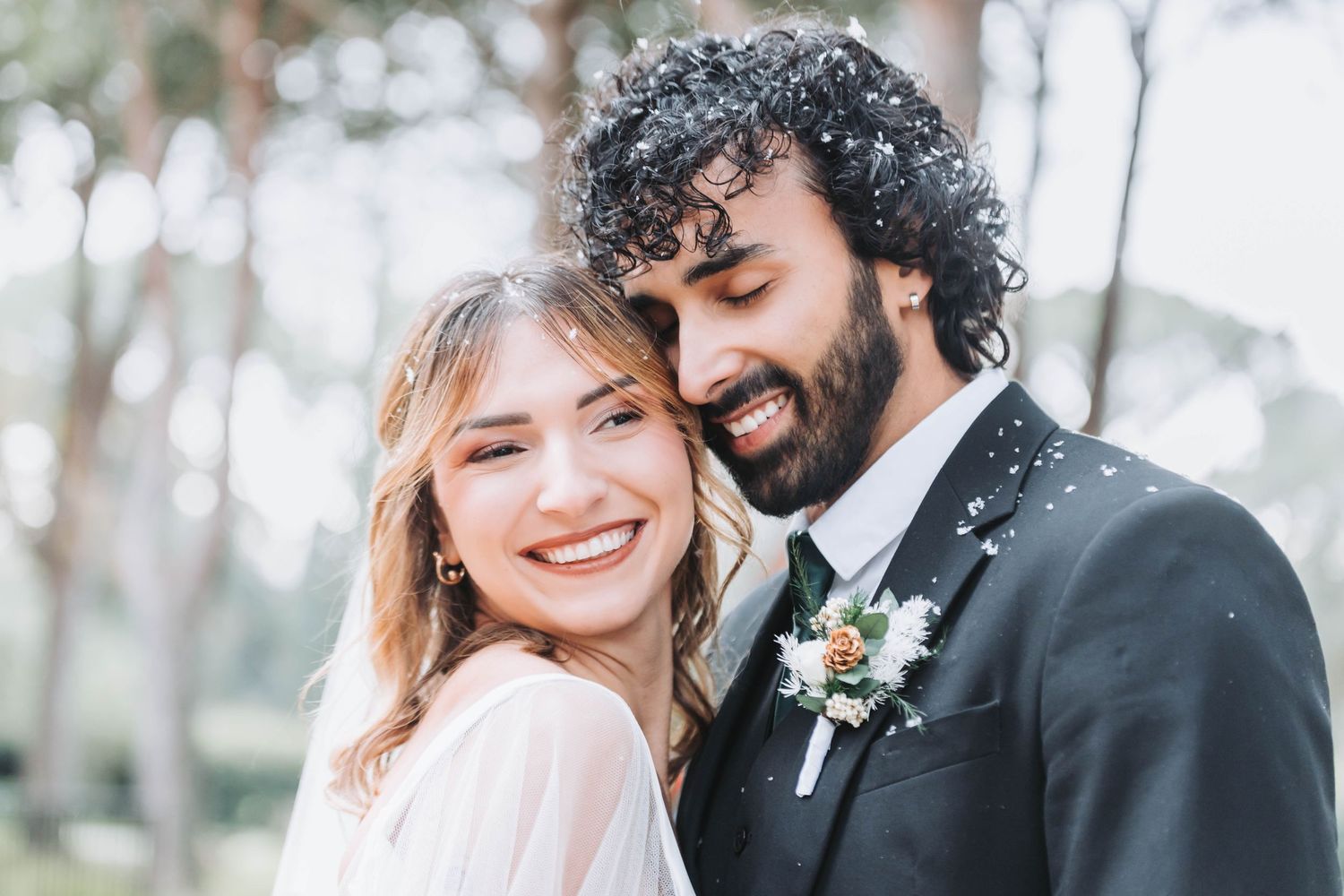 Joyful winter wedding portrait with snow falling around newlyweds.