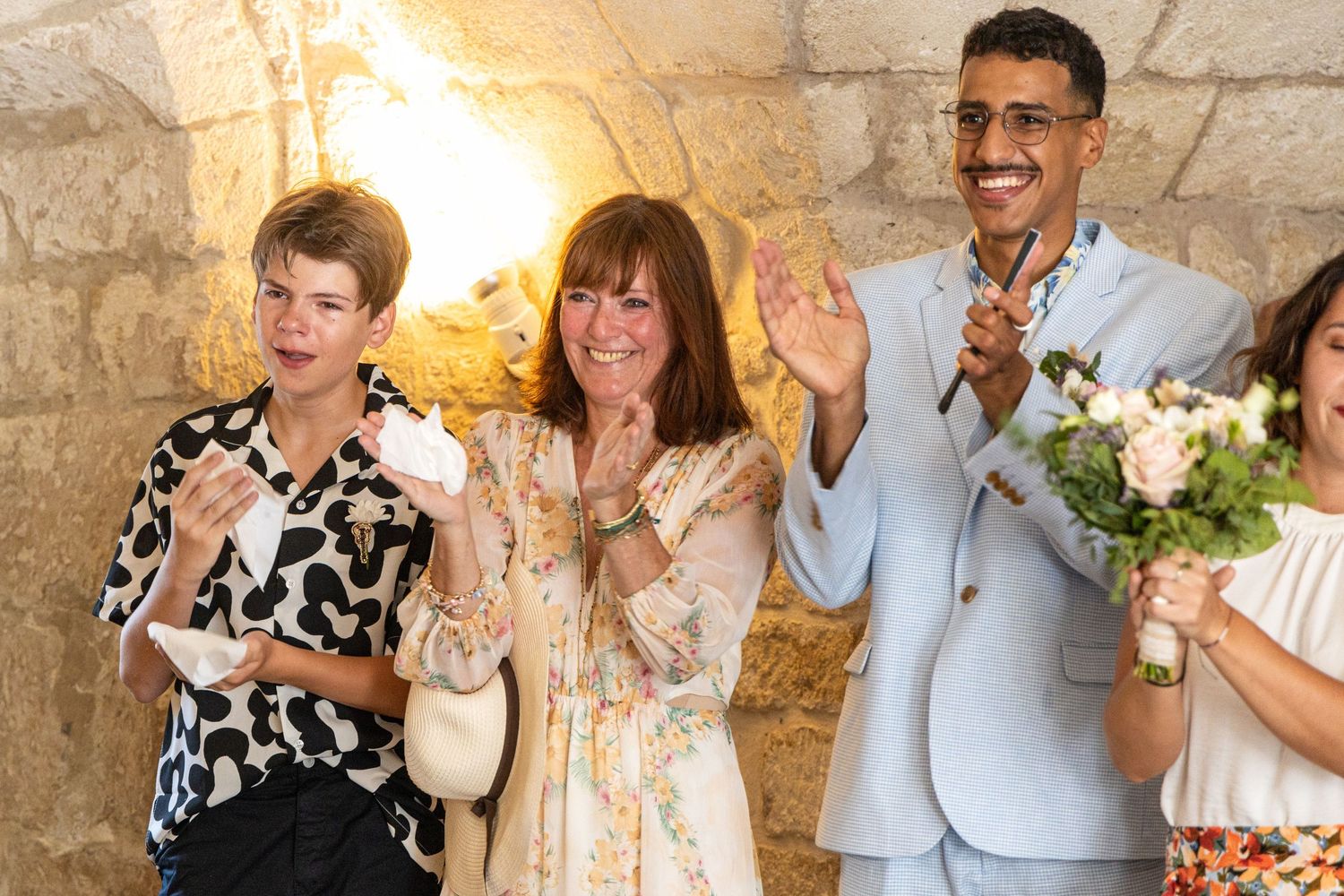 Wedding guests applauding during celebration in stone-walled venue.