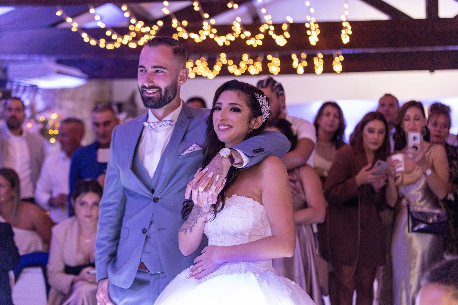 Wedding reception dance floor moment captured under twinkling lights and purple ambient lighting.