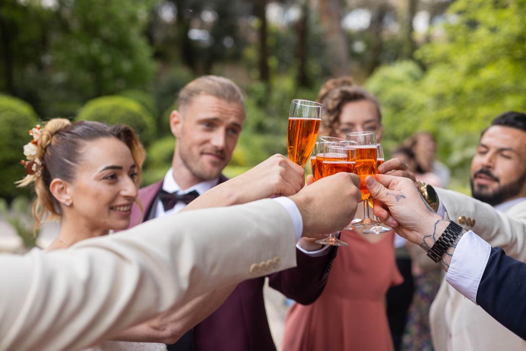 Celebratory toast with raised glasses at an outdoor wedding reception.