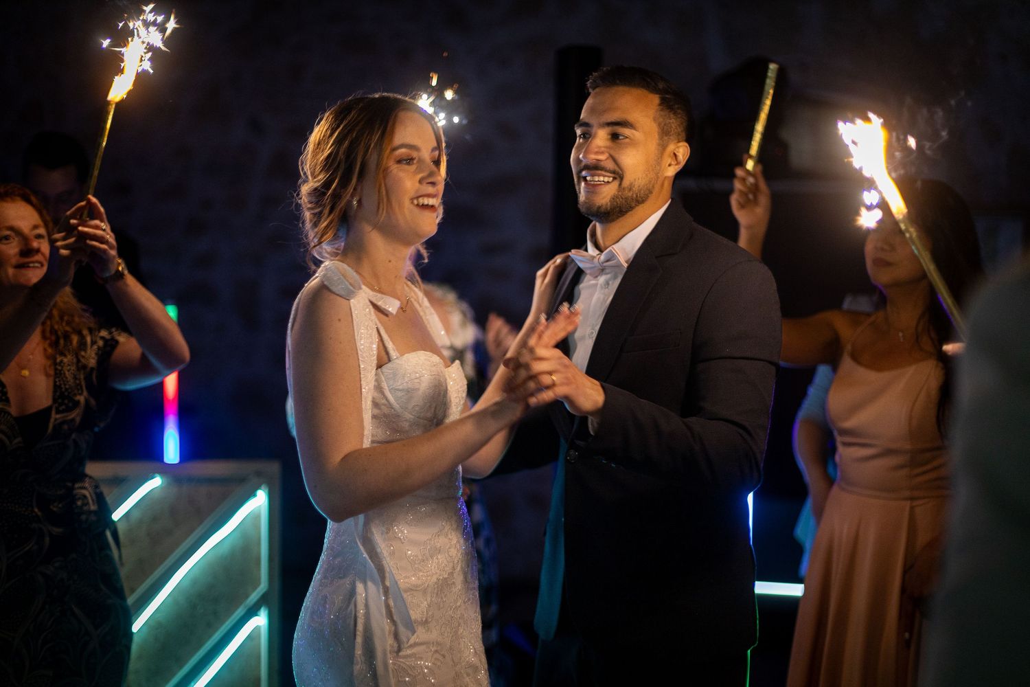 Wedding party dancing and celebrating with sparklers during an evening reception.