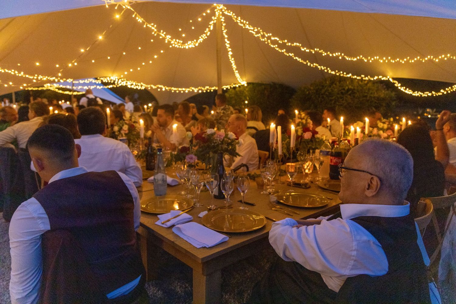 String lights create a warm ambiance over an outdoor evening party setting.
