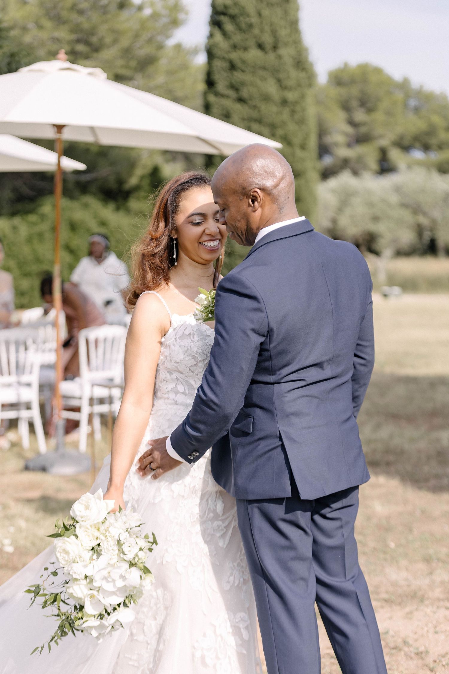 Romantic outdoor wedding portraits with bride in lace dress and groom in navy suit.