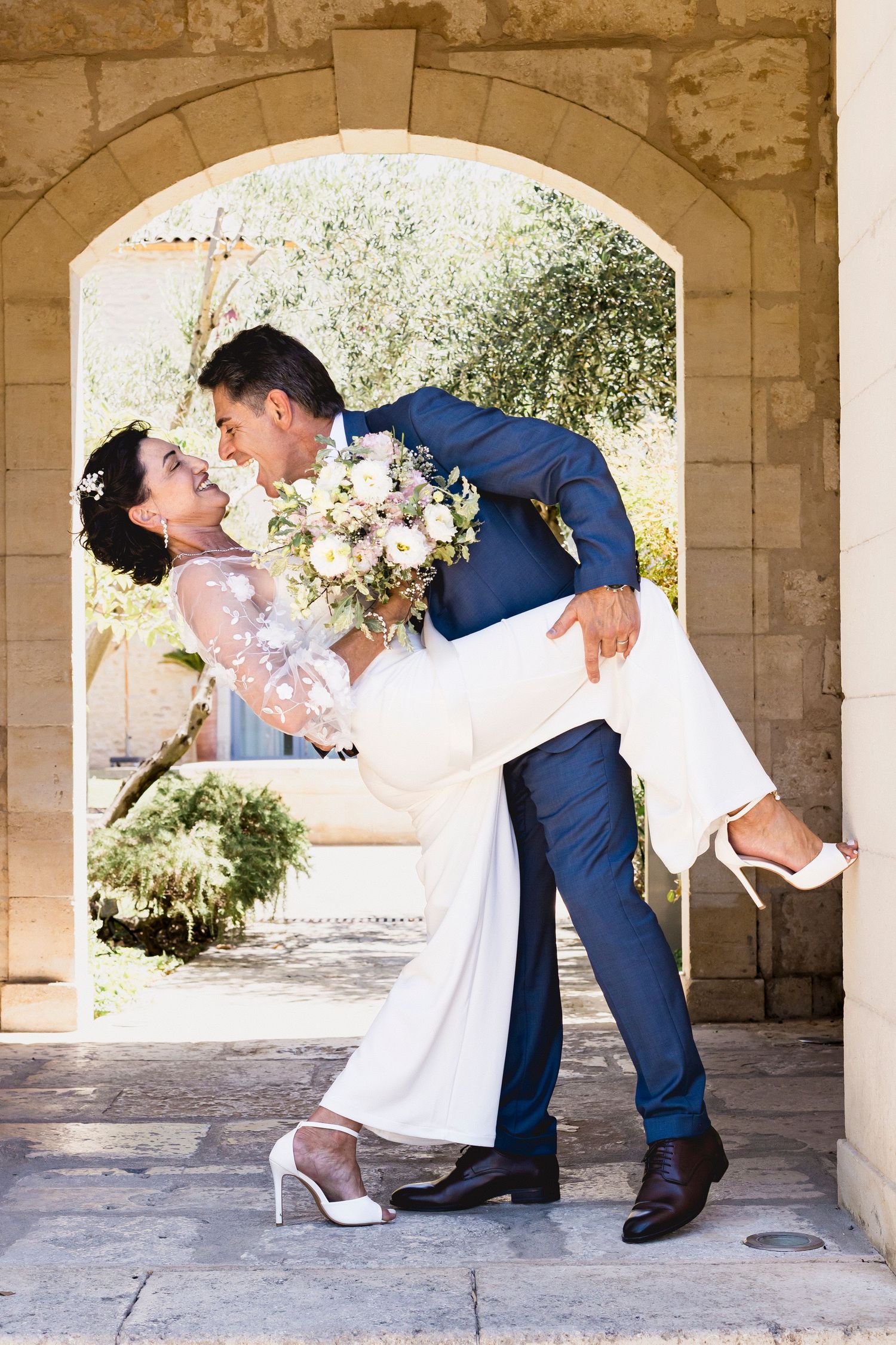 Romantic dip pose under stone archway captures dramatic wedding moment in natural light.