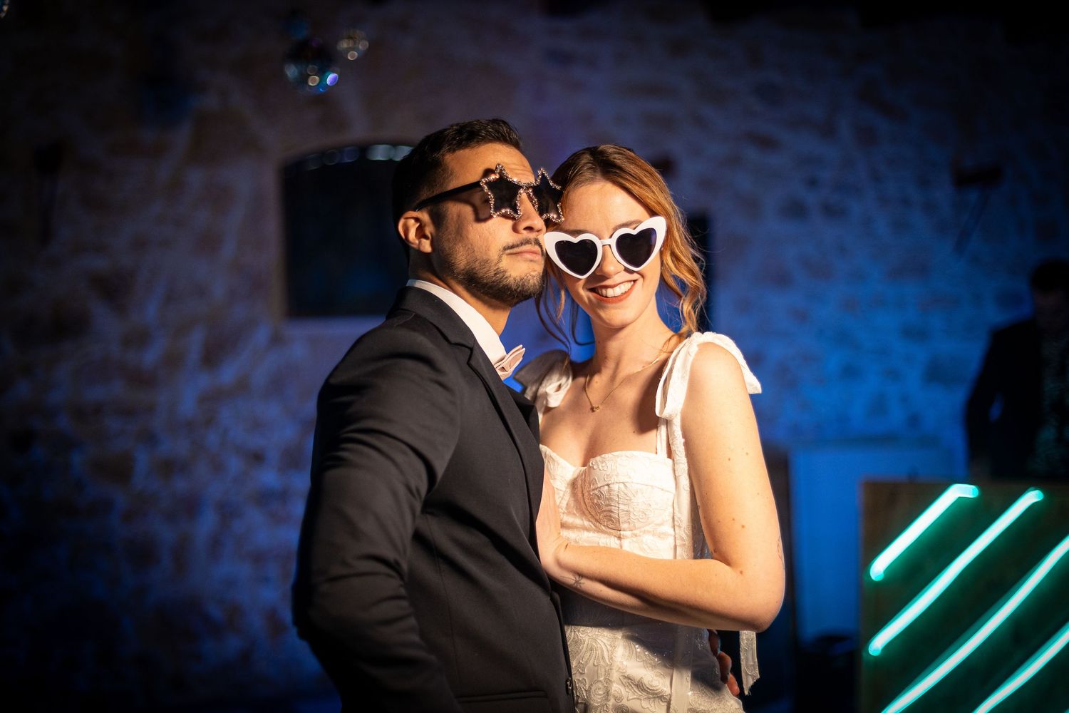 Festive evening wedding celebration with blue lighting and retro sunglasses.