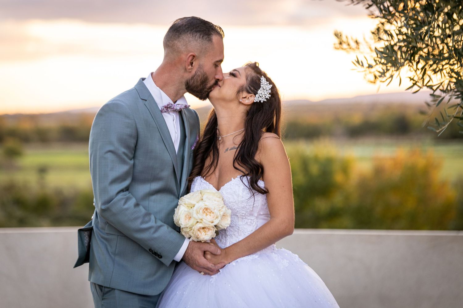 Sunset wedding portraits with couple embracing on gravel path against warm glowing sky.