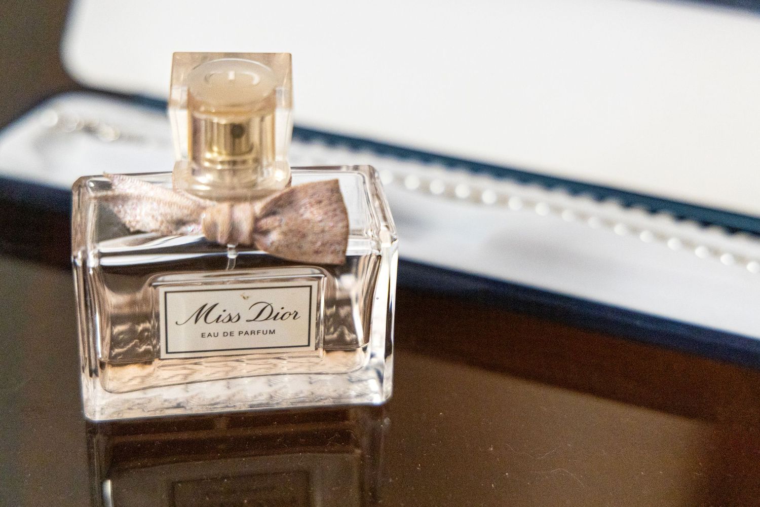 Luxury perfume bottle displayed on dark surface with reflective finish.