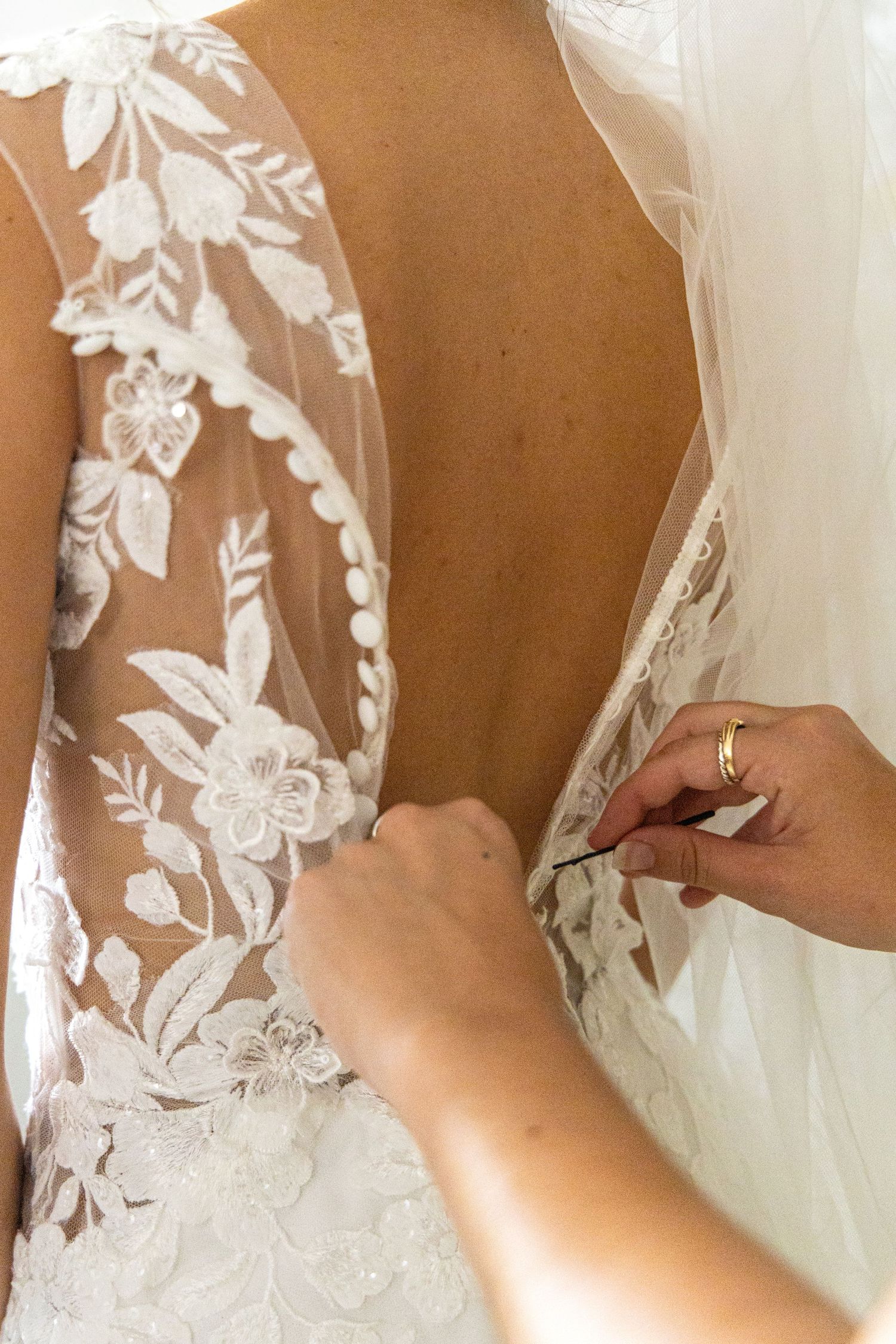 Detail shot of intricate white lace floral appliques on a wedding dress bodice.