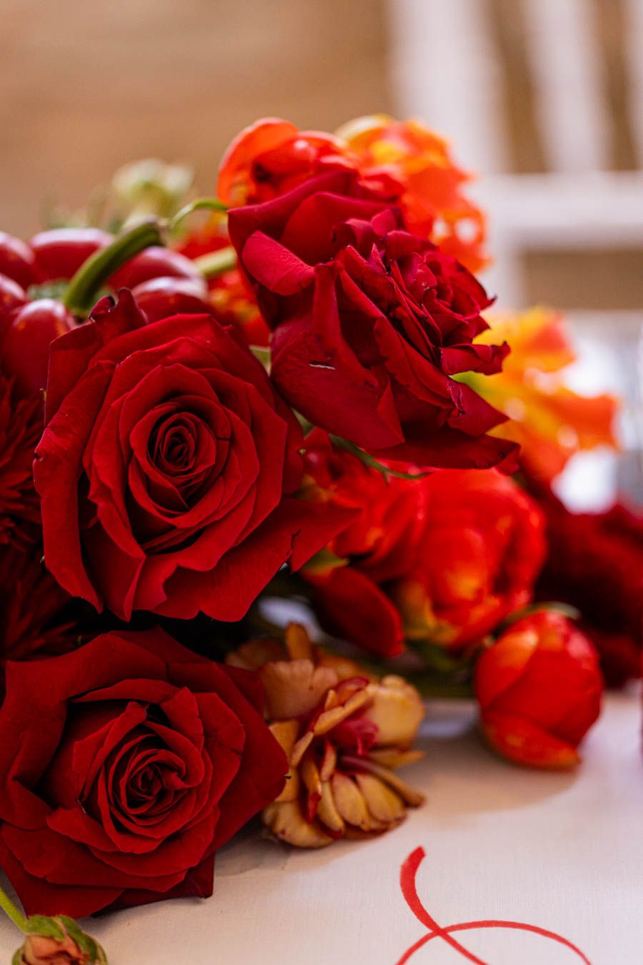 Close-up of vibrant red and orange roses in wedding floral arrangement.