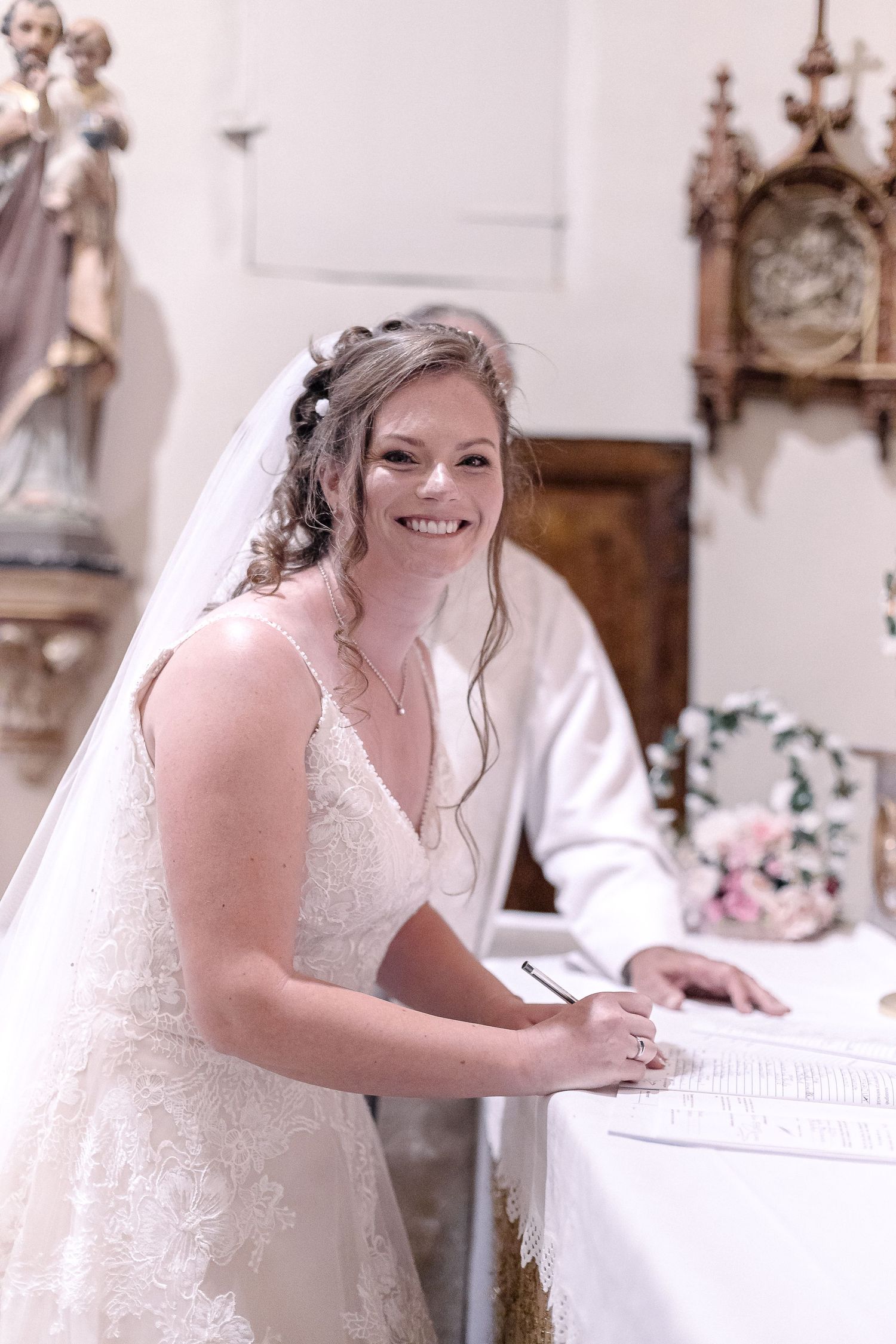 Bride signing wedding documents in an ornate church interior.