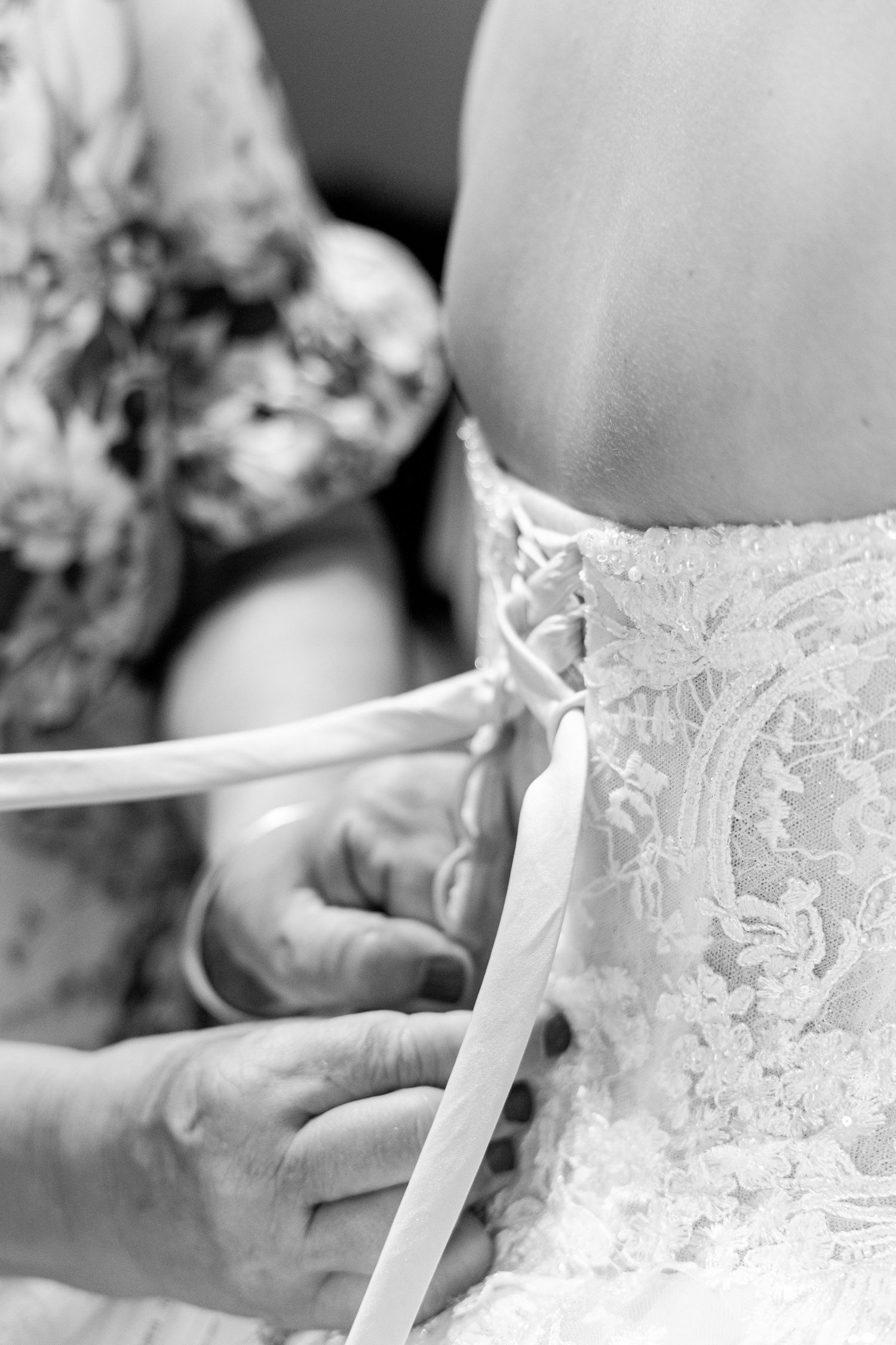 Close-up of intricate lace wedding dress being laced up.