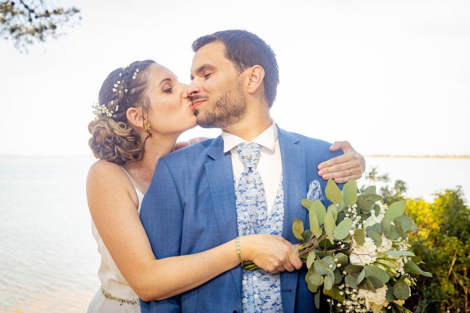 Intimate moment captured in sunlit garden setting with floral bouquet.