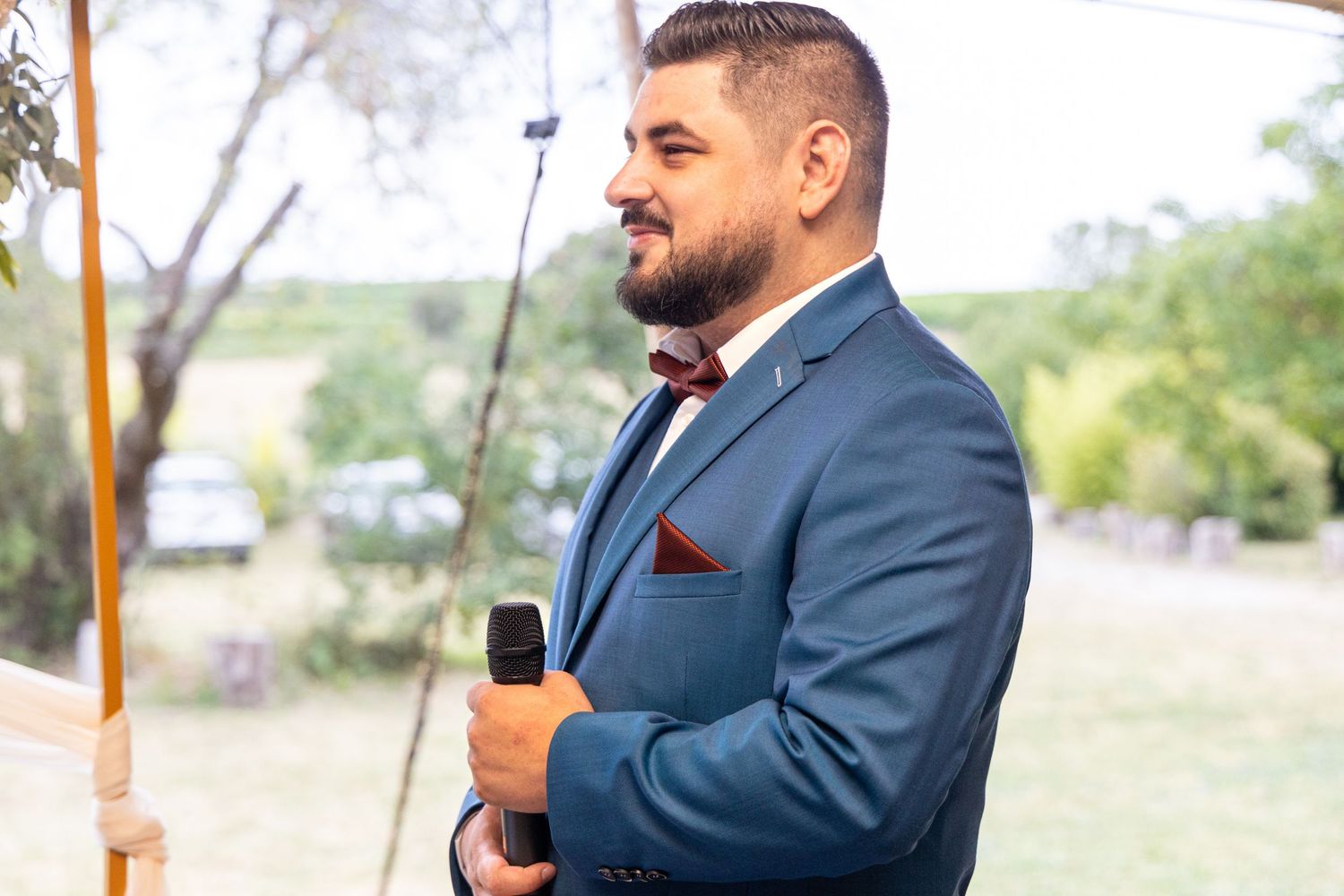 Wedding ceremony speeches taking place at an outdoor venue with natural backdrop.