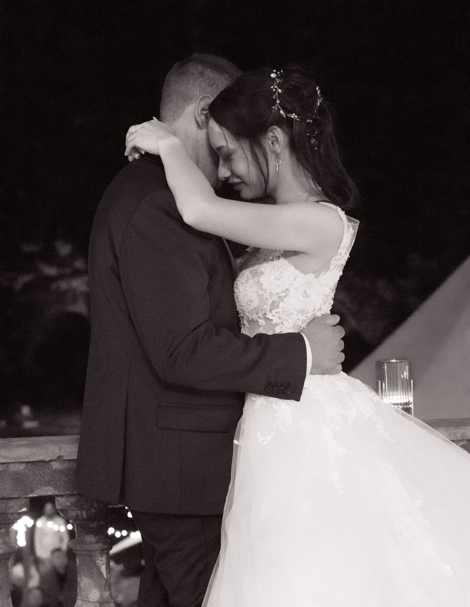 Couple sharing their first dance in elegant wedding attire on a dimly lit dance floor.