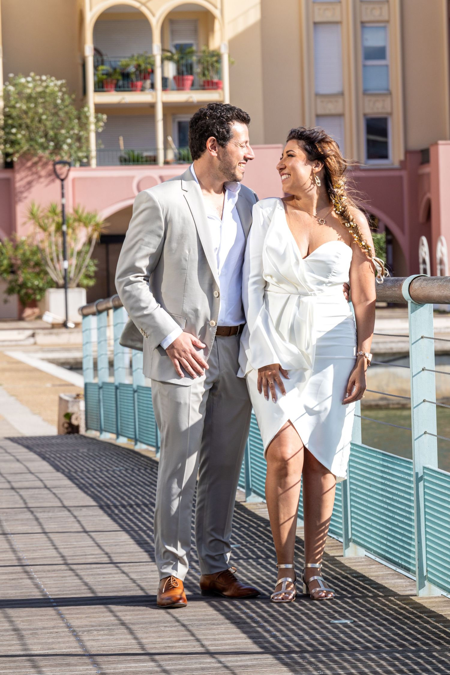 Couple in white outfits share a romantic moment on a resort walkway.