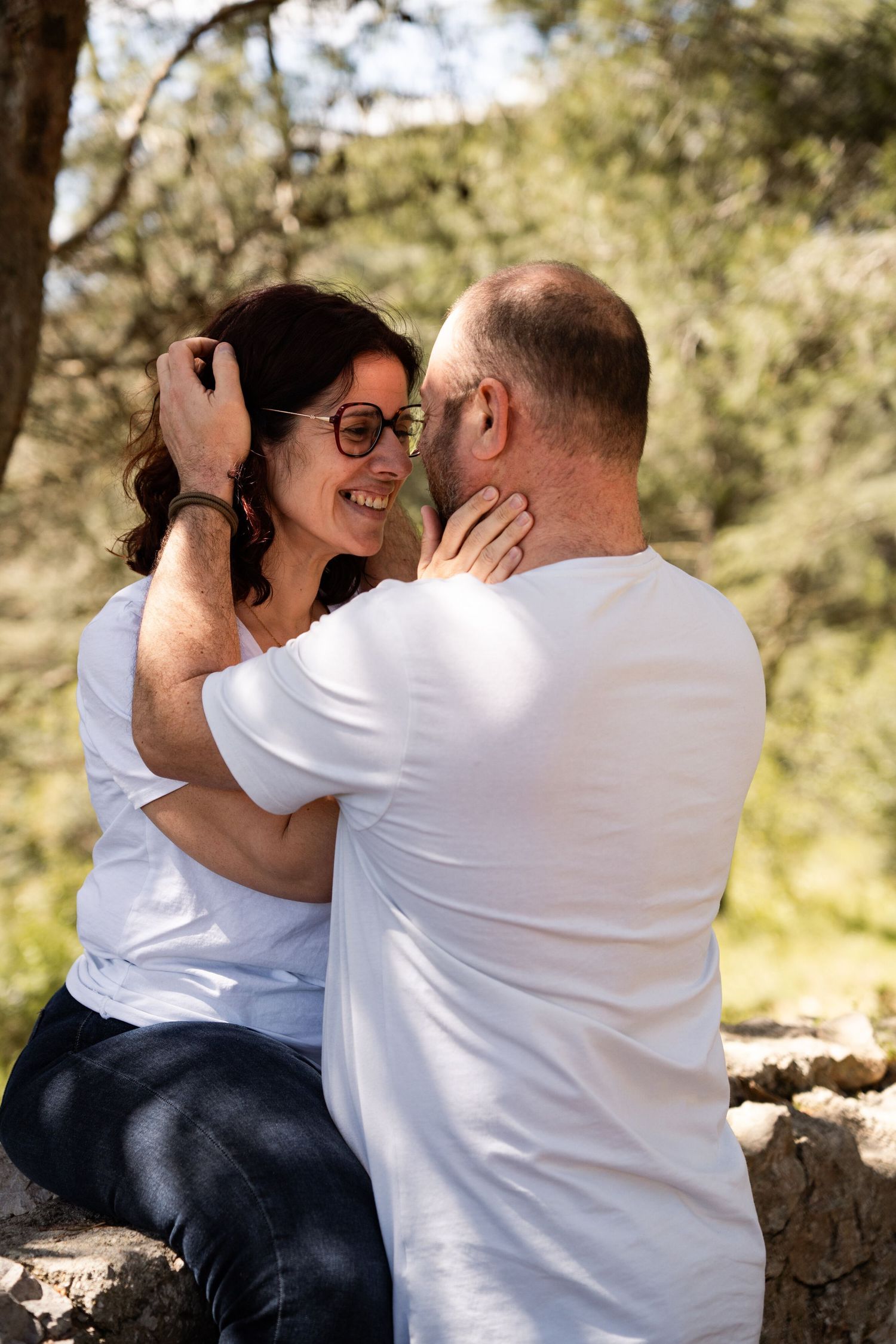 A couple sharing an intimate moment outdoors on a sunny day in a natural setting.