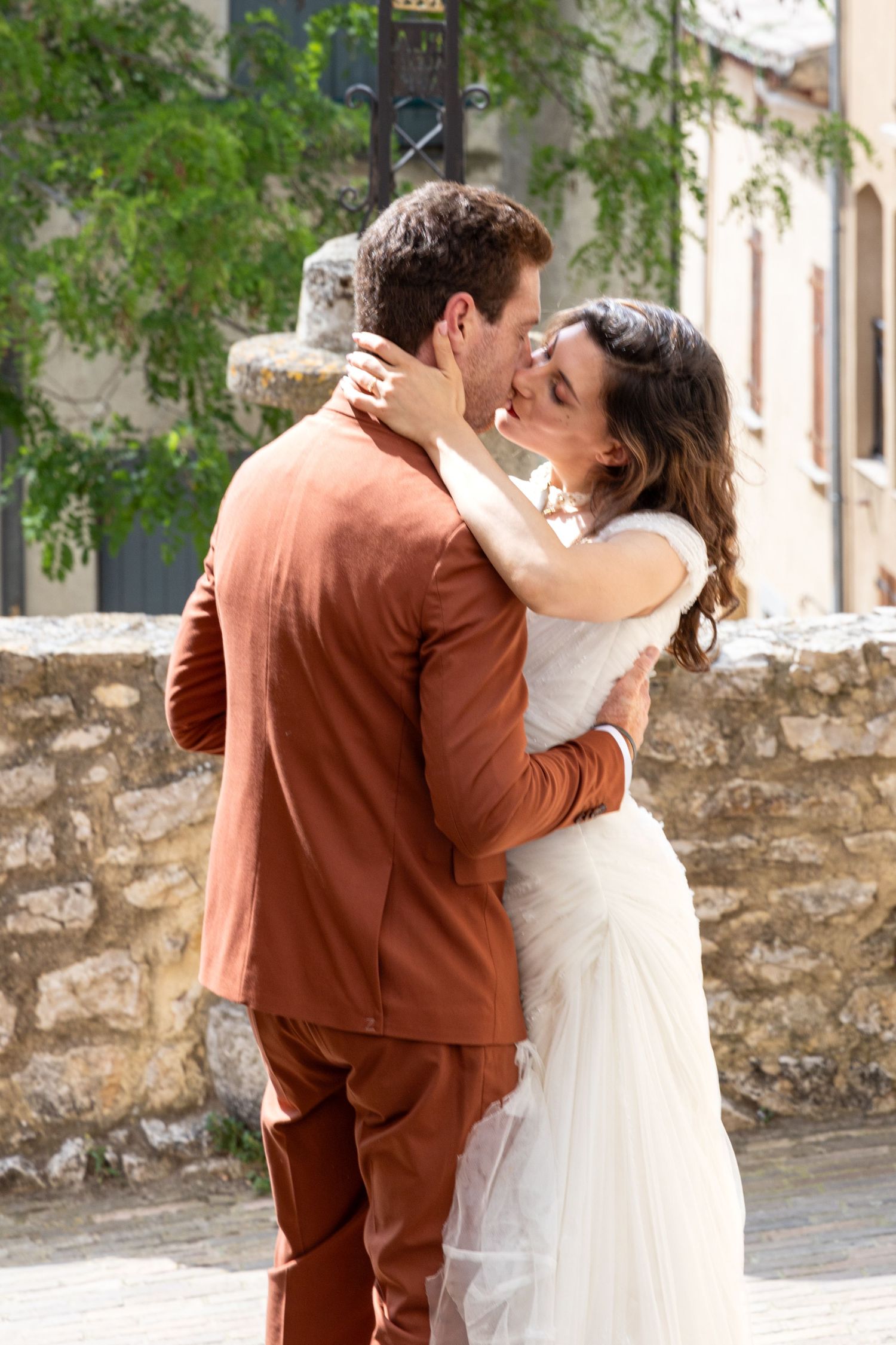 Romantic embrace against stone wall and greenery background.