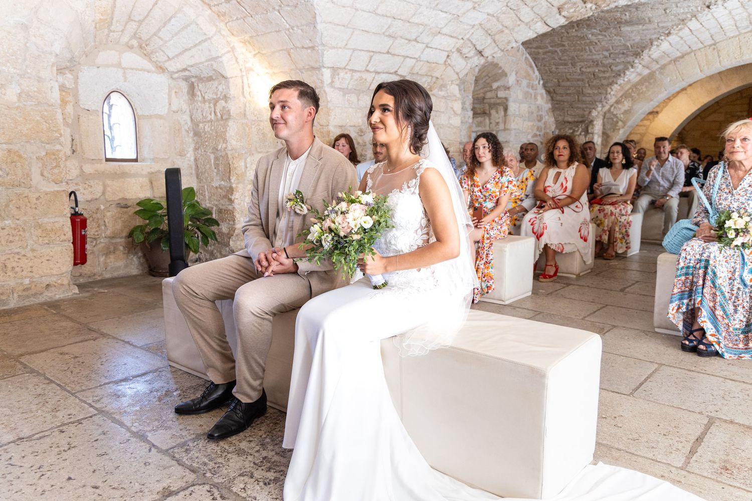 Wedding ceremony in an elegant stone venue with arched windows and natural light.