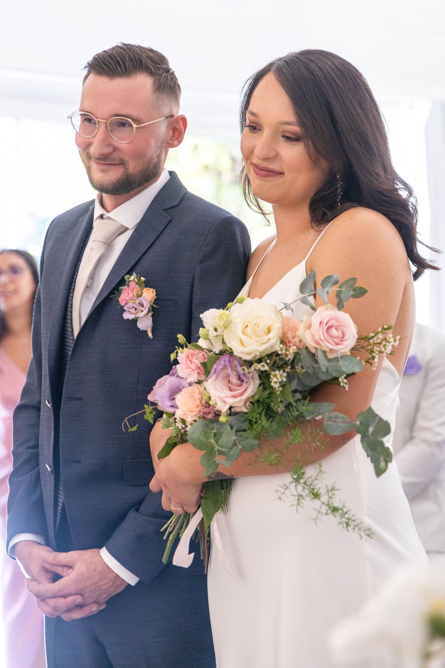 Elegant wedding bouquet features pink roses and greenery against a white gown.