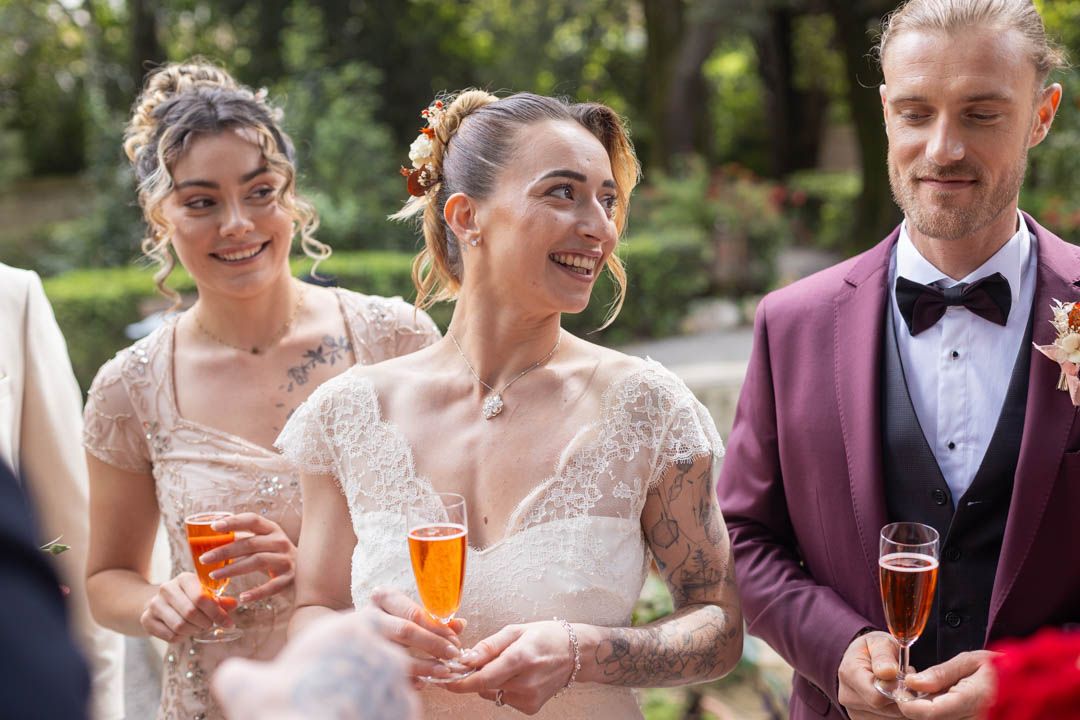 Wedding party toasting with orange-colored cocktails in an outdoor garden setting.