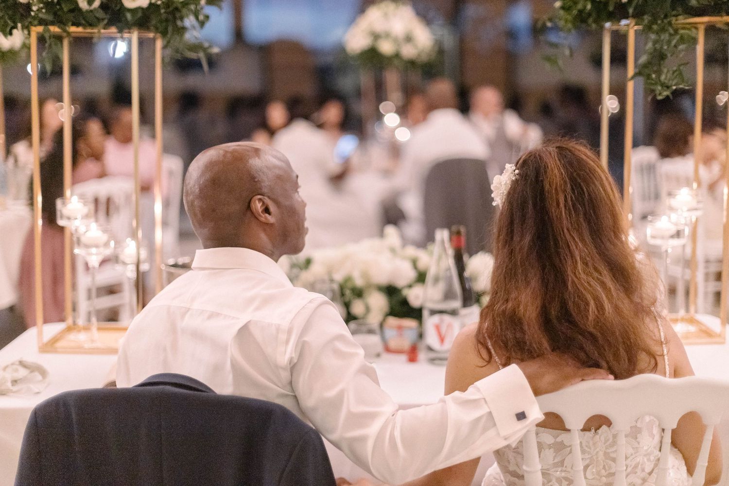 Elegant outdoor wedding reception with guests dining at decorated tables.