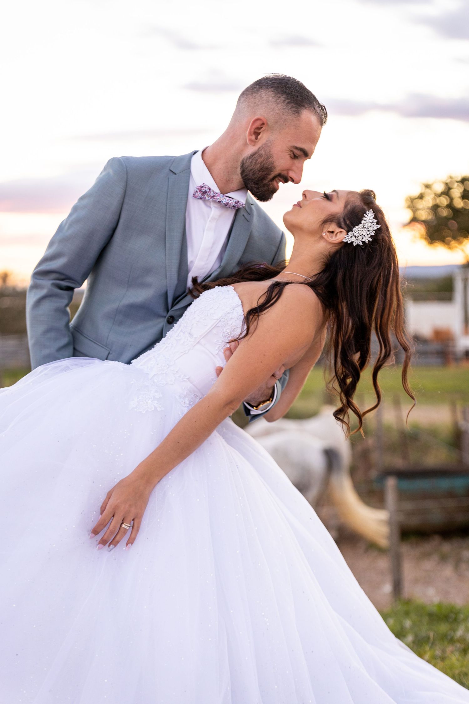 Romantic dip pose wedding portrait at sunset with dramatic lighting.