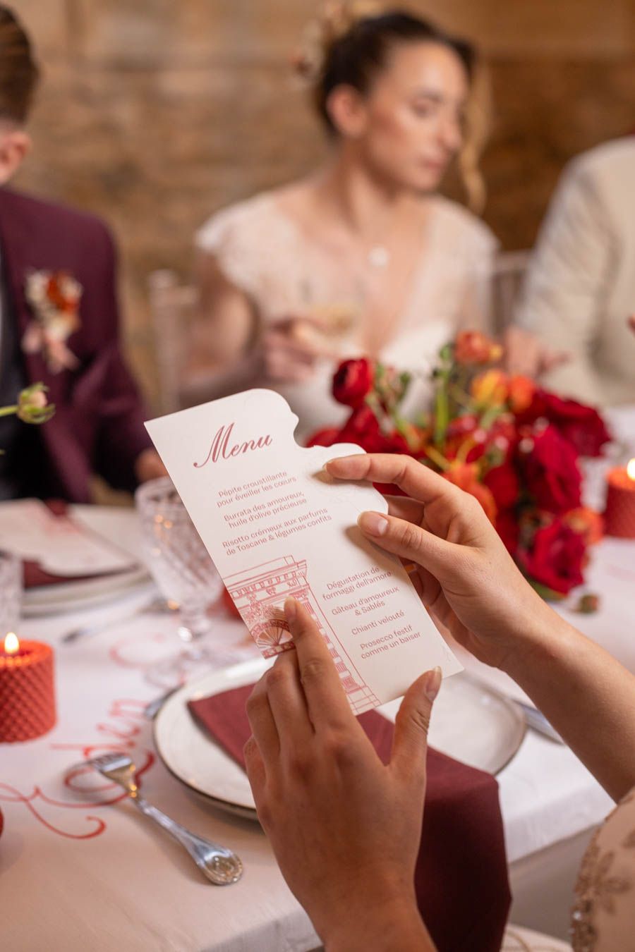 Hands holding an elegant wedding menu card at a formal table setting.