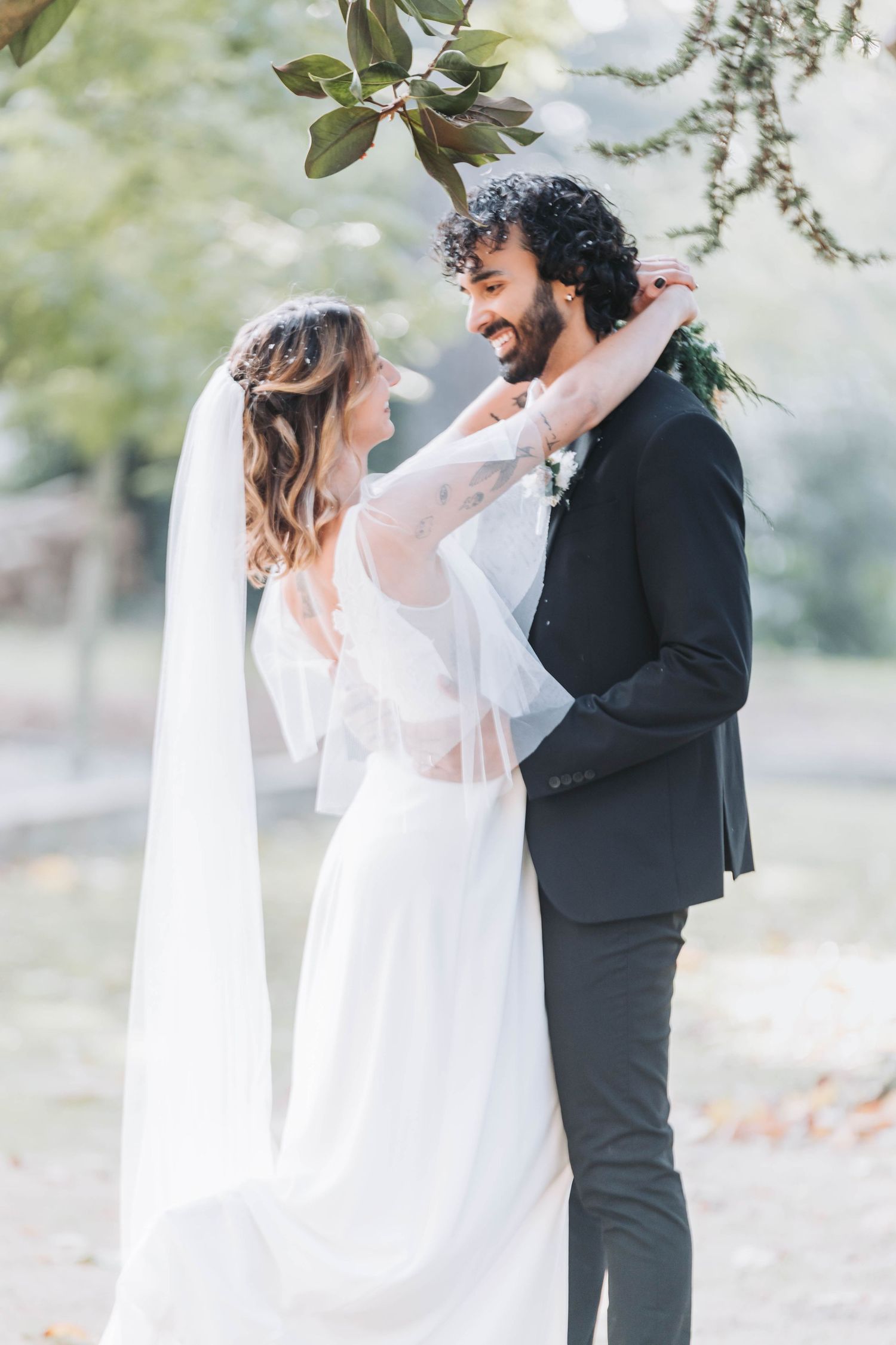 Ethereal outdoor wedding photos with bride in flowing white dress and groom in black suit.
