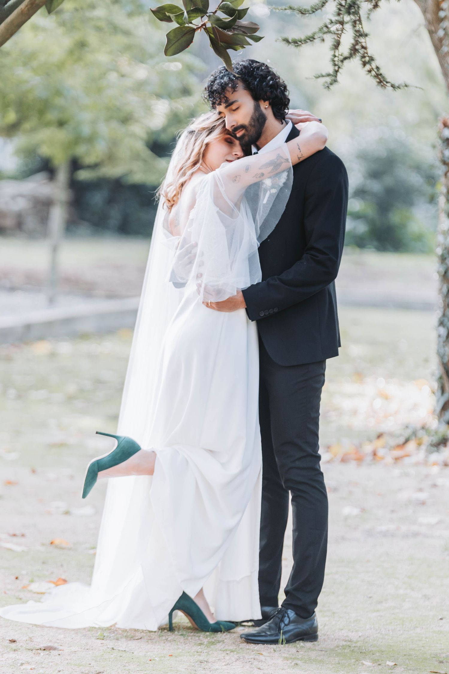Wedding couple embracing outdoors with bride wearing elegant white dress and teal shoes.