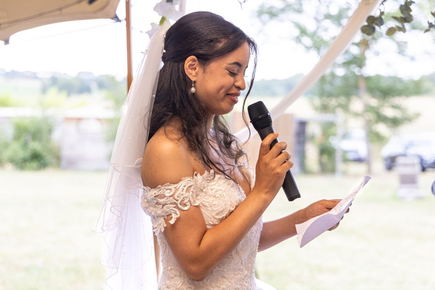 Intimate outdoor wedding ceremony with speakers and decorative elements under natural lighting.