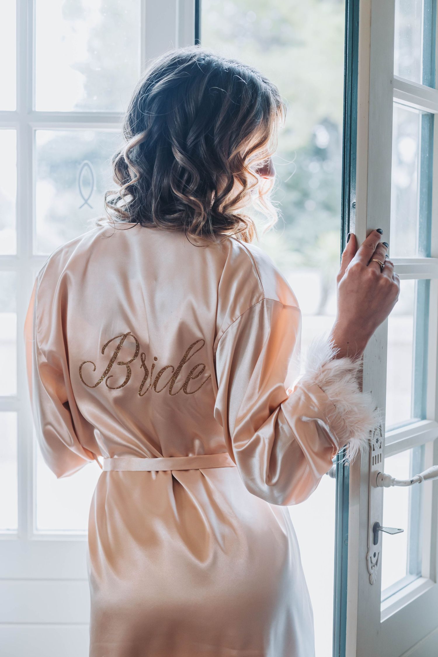 Back view of silk robe with 'Bride' embroidery near window.