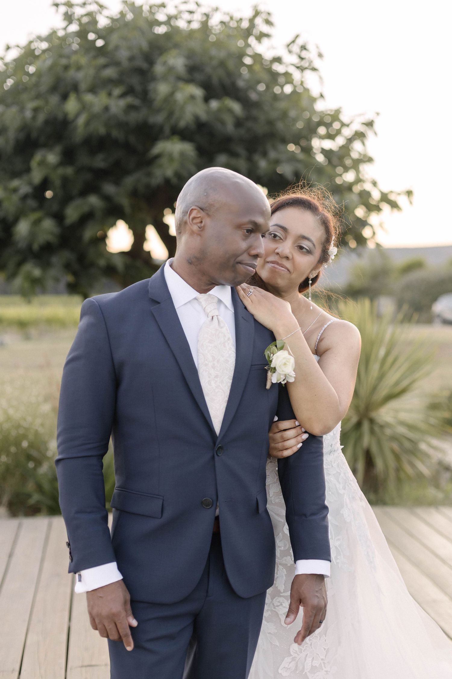 A couple embraces and laughs together during their wedding photoshoot on an outdoor deck.