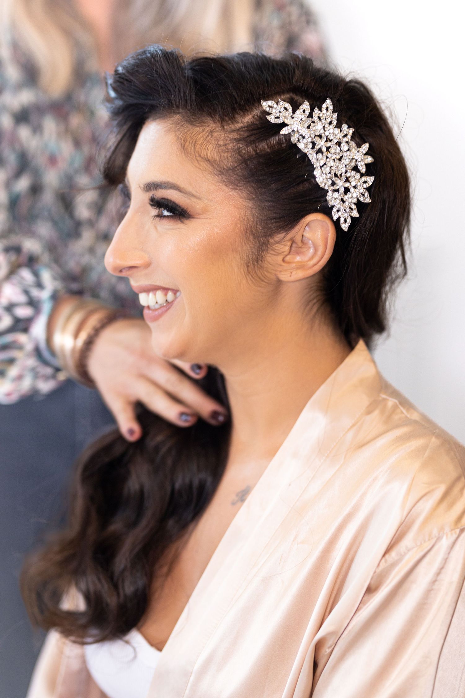 Bride smiles while getting ready with ornate hair accessory.