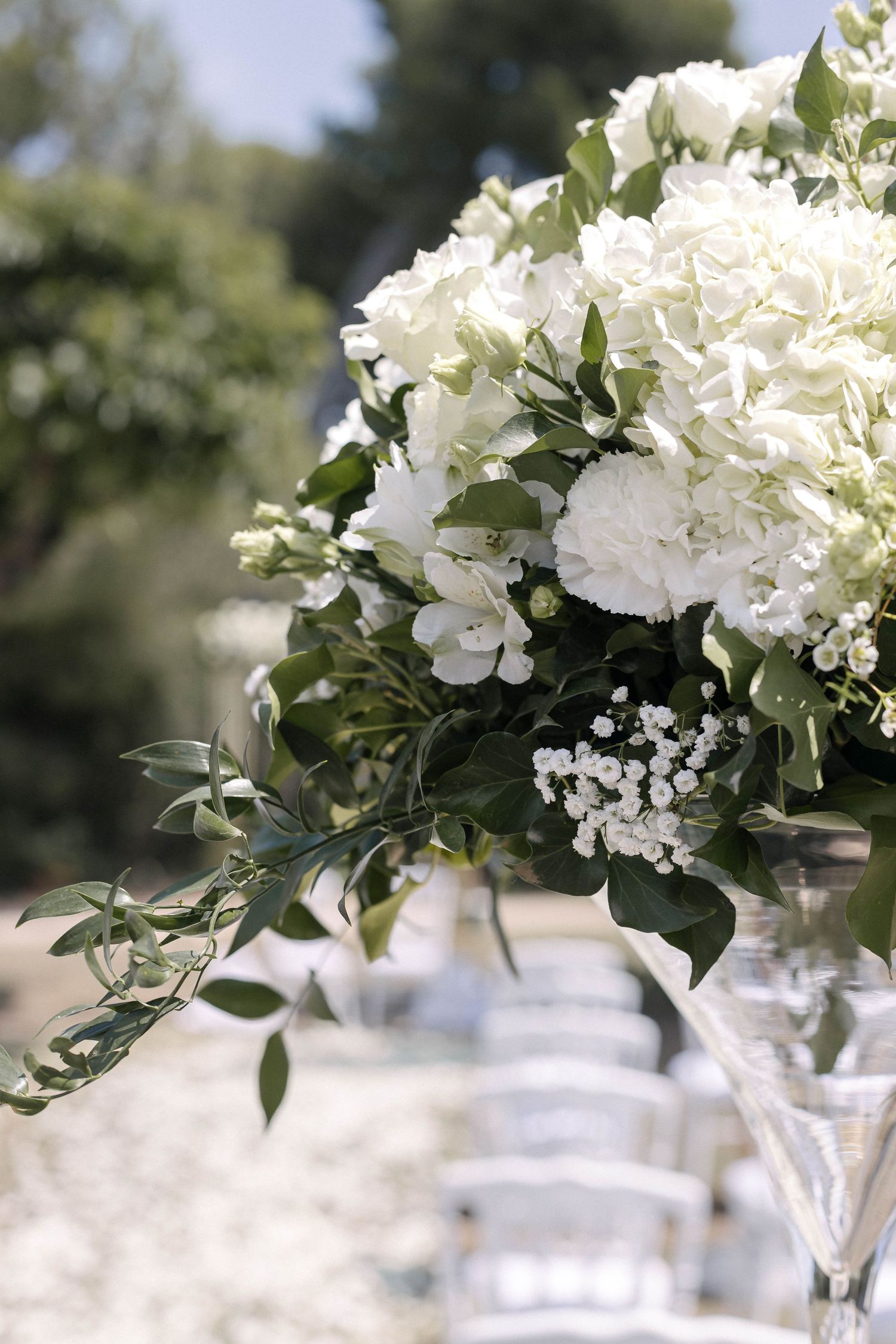 White hydrangea and greenery floral centerpieces arranged in clear glass vases.