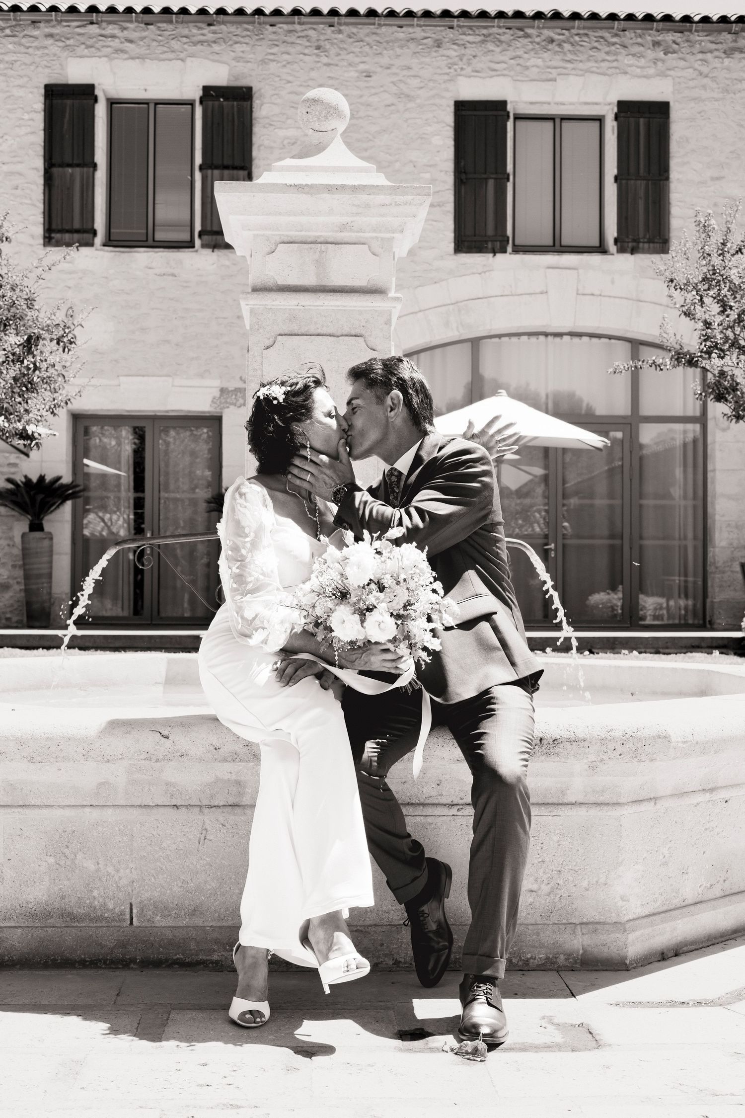 Black and white sequence of newlyweds posing playfully near a stone wall.