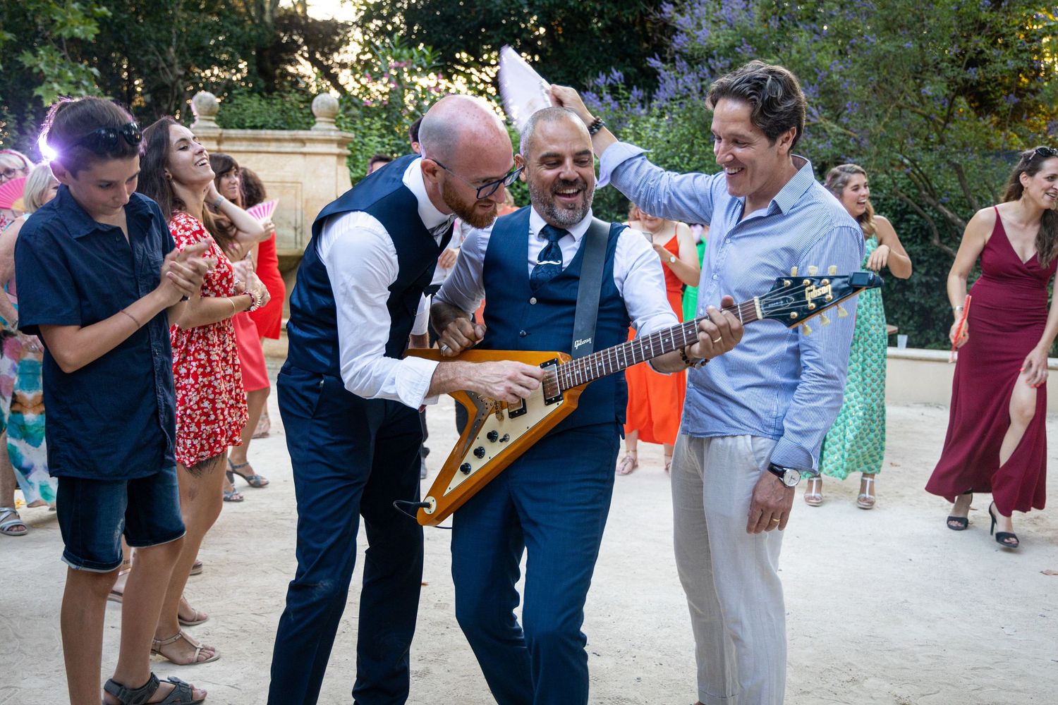 Musicians performing with a unique guitar at an outdoor wedding reception.