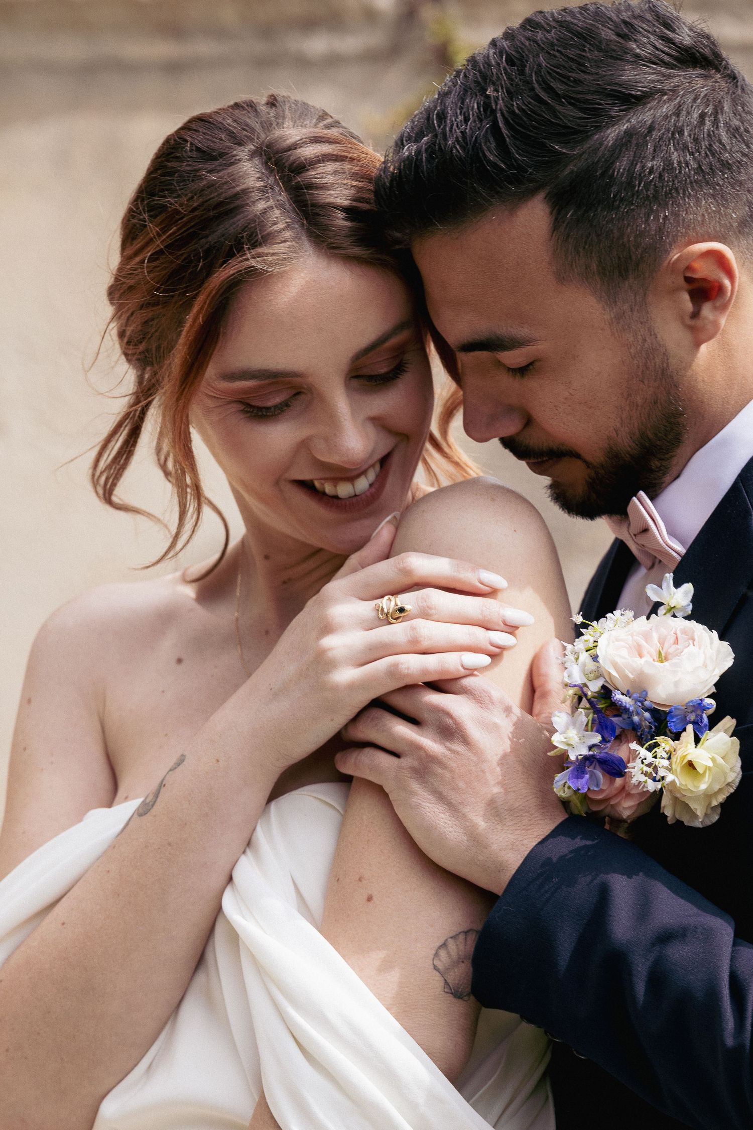 Close-up of joyful wedding couple sharing an intimate embrace with peach and blue floral details.