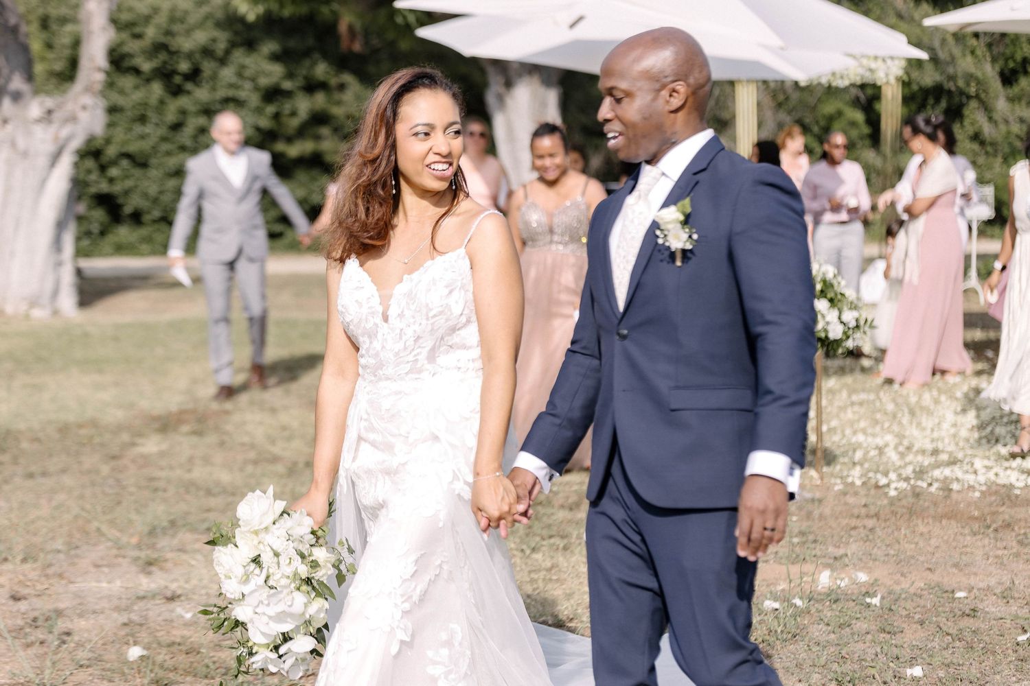 Elegant outdoor wedding ceremony with white decor and garden setting.
