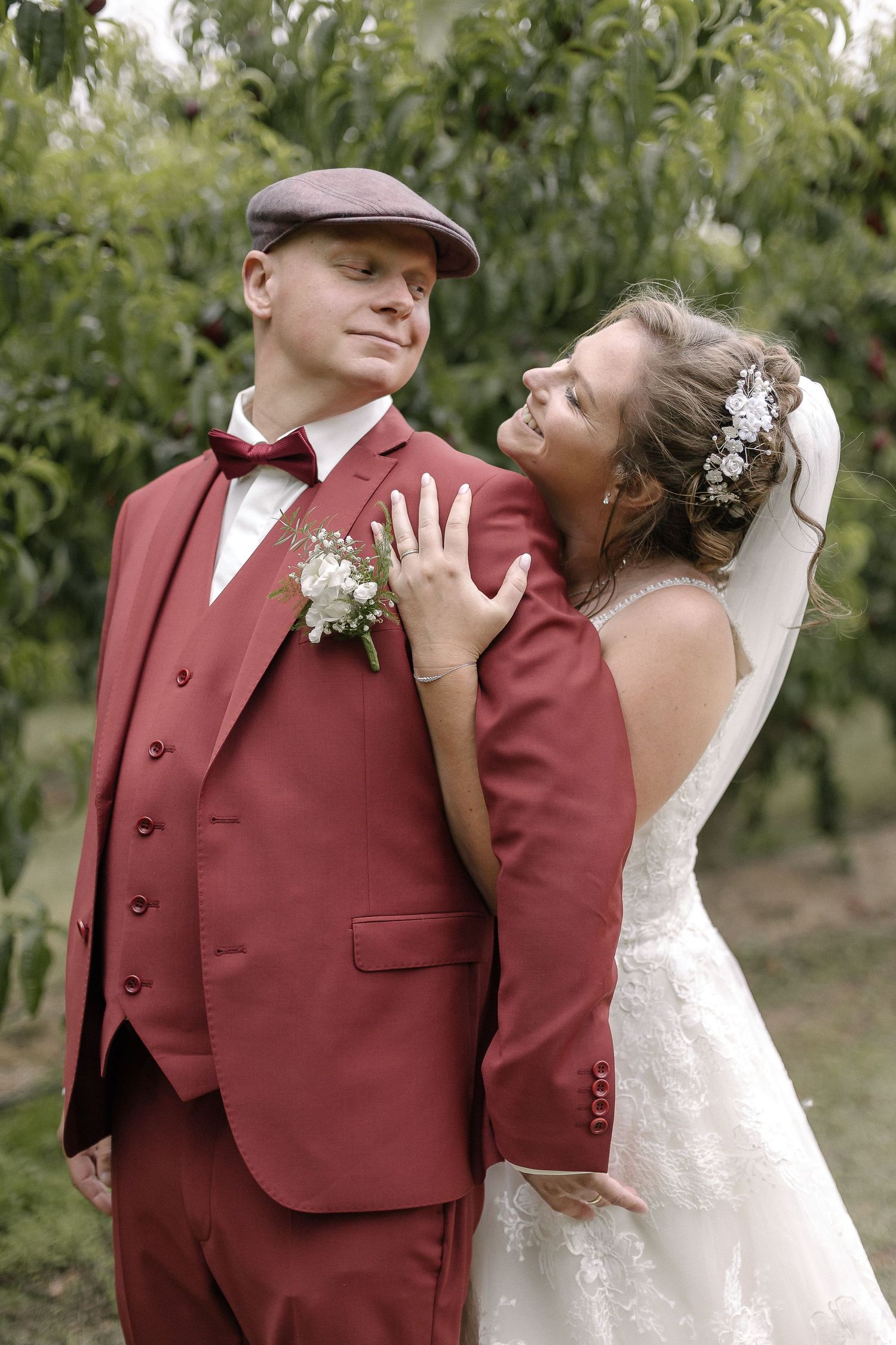 Newlyweds share a tender moment in an orchard setting.