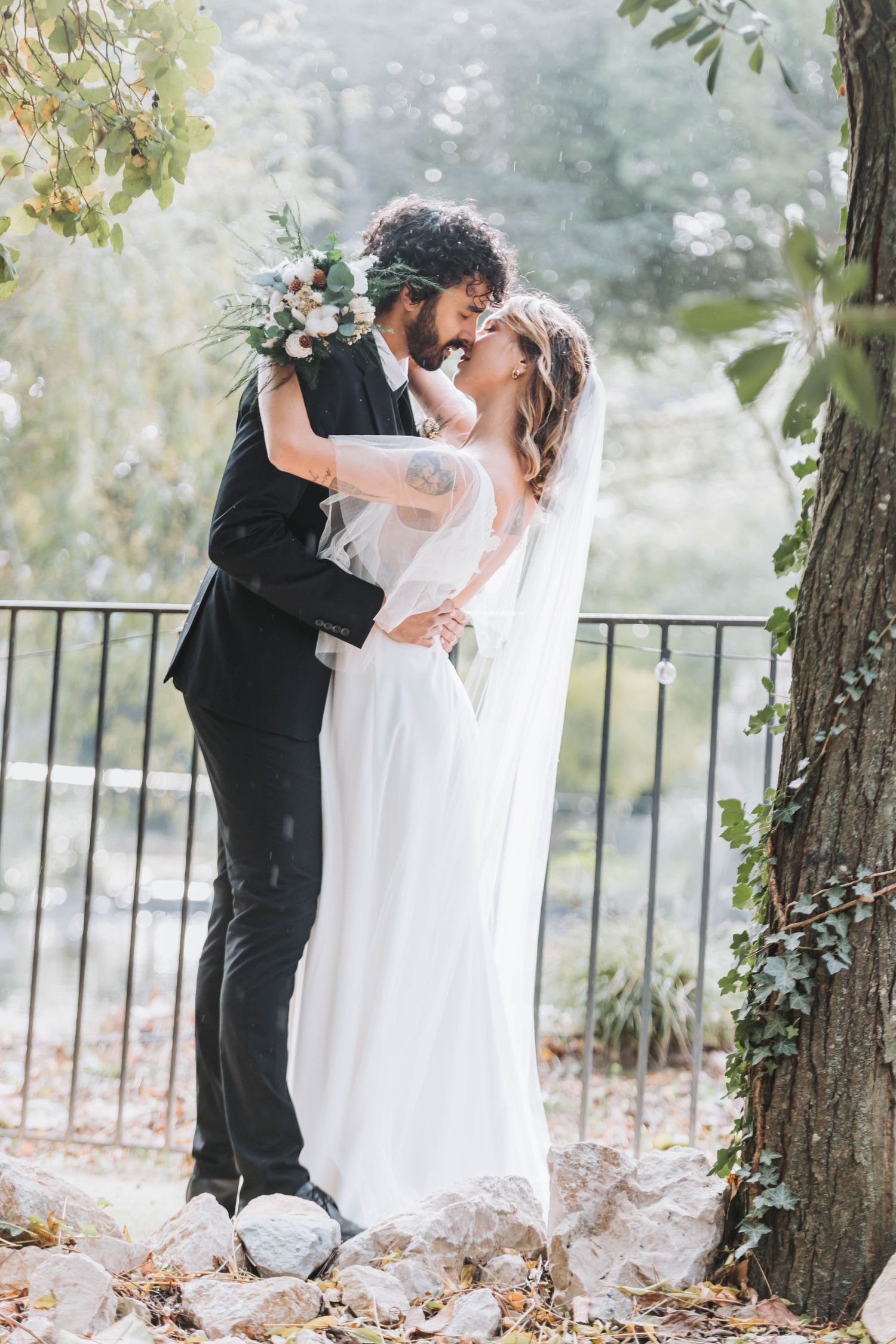 Winter wedding portraits among bare trees with flowing white dress and dark suit.