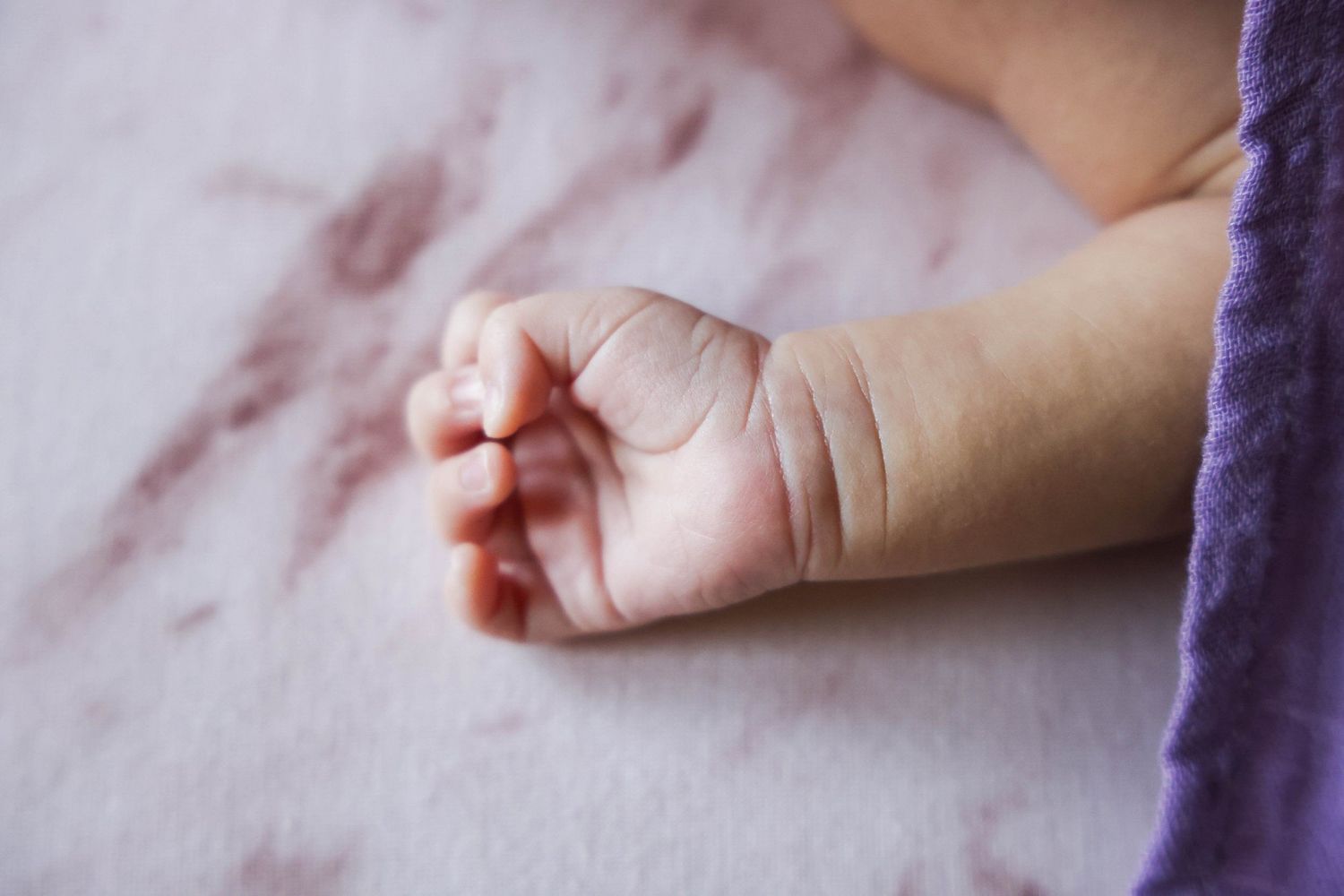 Close-up of a tiny baby's hand resting on pink fabric in Abilene, Texas.