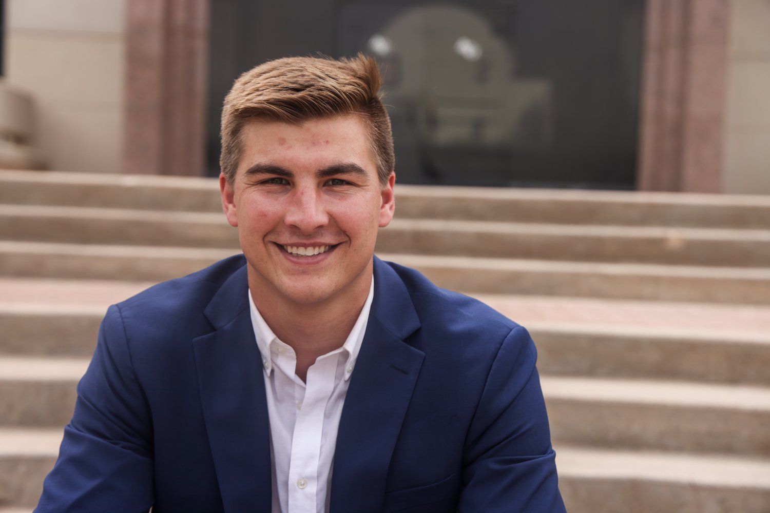 Portrait of person in navy suit smiling on outdoor steps in Abilene, Texas.