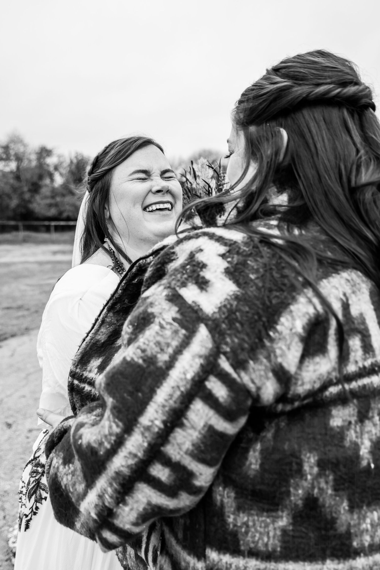 Bridal photo with bridesmaid sharing a joyful candid moment outdoors  in black and white photography in Abilene, Texas.