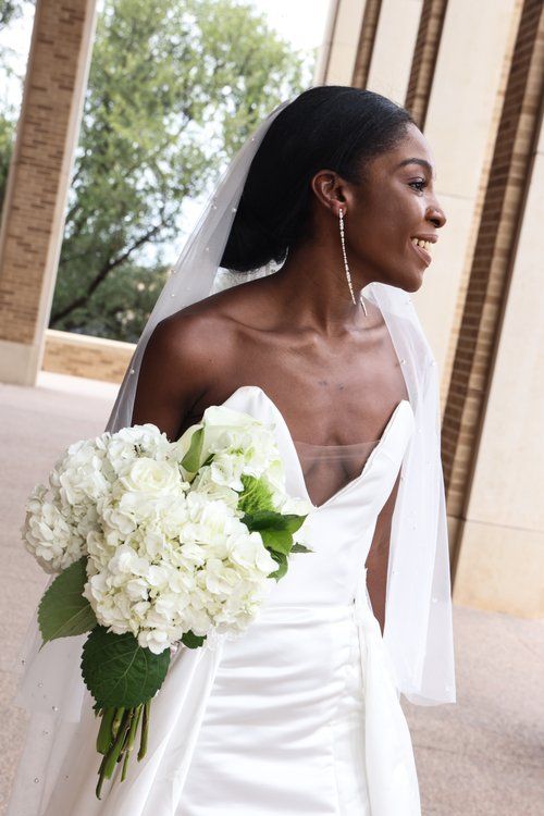 An elegant bride in a white wedding dress holding a bouquet of white hydrangeas in Abilene, Texas.