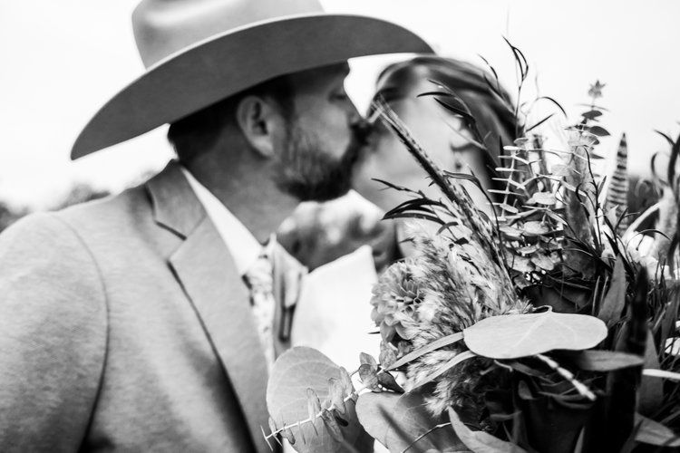 A romantic black and white photo of a cowboy leaning in close to a bouquet of wildflowers in Abilene, Texas.