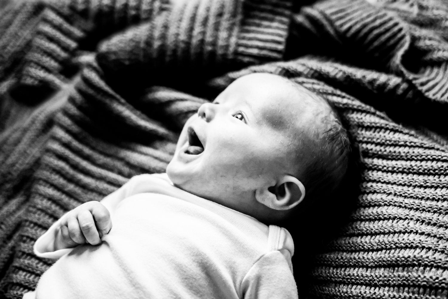 Black and white portrait of smiling infant on knit blanket in Abilene, Texas.